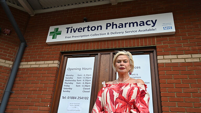 Rachel Gilmour standing in front of a sign that reads 'Tiverton Pharmacy'