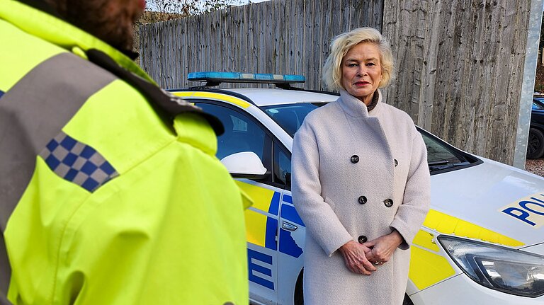 Rachel Gilmour MP standing in front of a police car